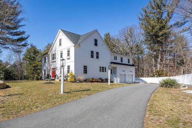 view of front of property featuring driveway, a front lawn, and fence