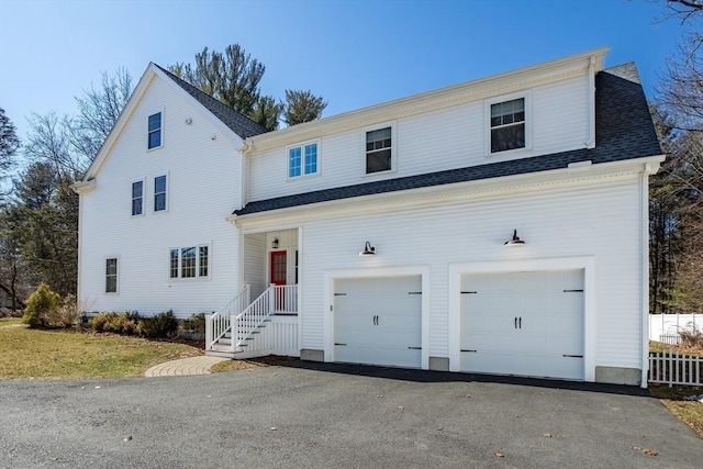 view of front of property featuring fence, driveway, and a shingled roof