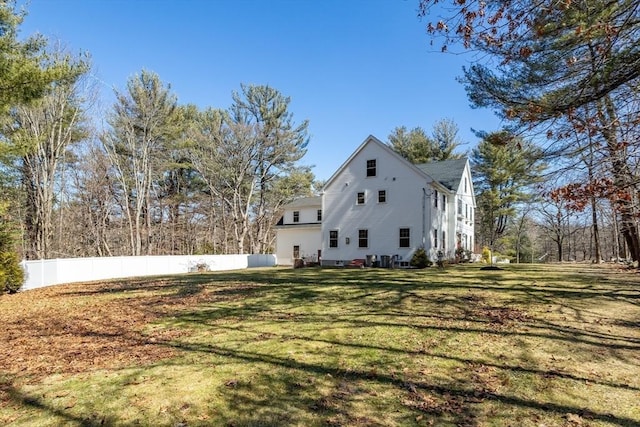 view of property exterior with a lawn and fence