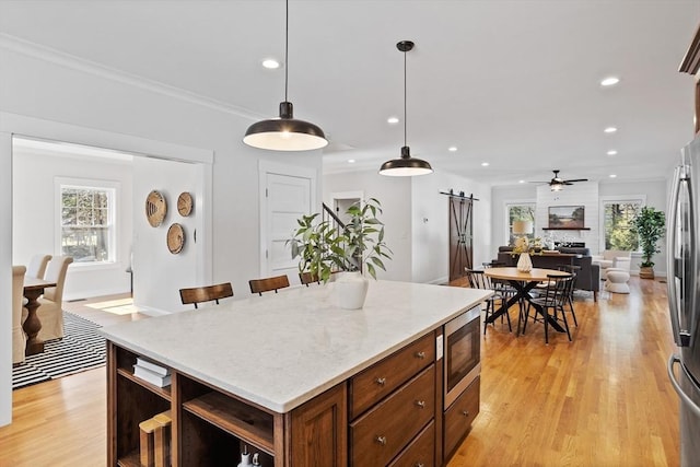 kitchen with light wood finished floors, open shelves, recessed lighting, a barn door, and stainless steel microwave