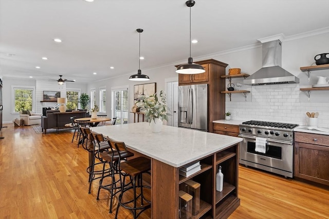 kitchen with open shelves, wall chimney range hood, light wood finished floors, and stainless steel appliances