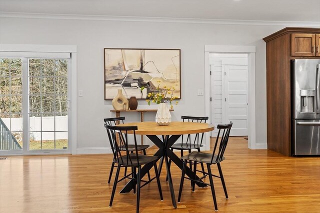 dining space with light wood finished floors, a healthy amount of sunlight, and crown molding