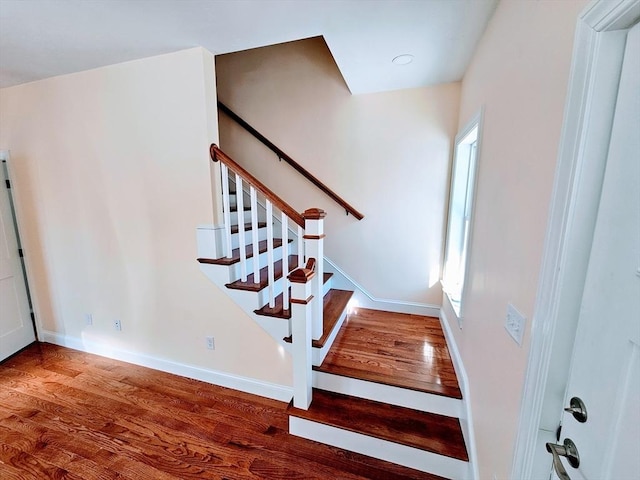 staircase featuring baseboards and wood finished floors