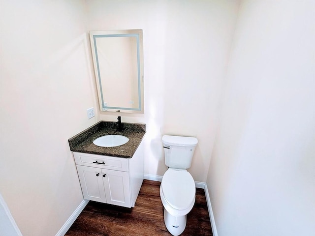 bathroom with baseboards, vanity, toilet, and wood finished floors