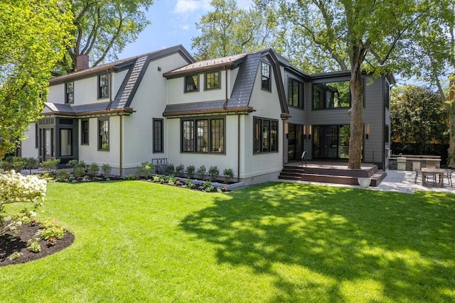 rear view of property featuring a lawn, a gambrel roof, and a chimney