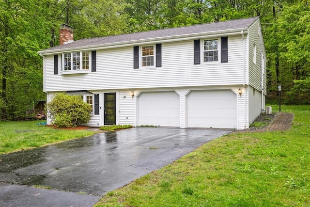 colonial-style house with an attached garage, a front lawn, a chimney, and driveway