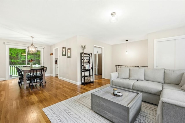 living area featuring light wood-style floors, baseboards, and a notable chandelier