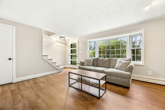 living area with stairway, a baseboard radiator, baseboards, and wood finished floors