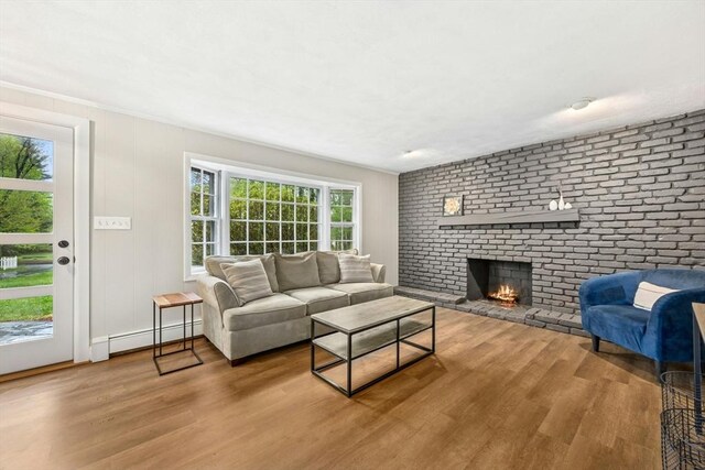 living area with a baseboard radiator, a fireplace, and wood finished floors