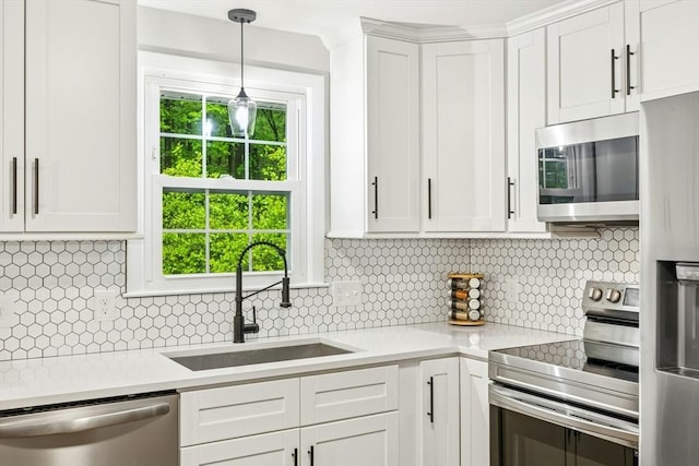 kitchen featuring a sink, white cabinetry, light countertops, appliances with stainless steel finishes, and decorative backsplash
