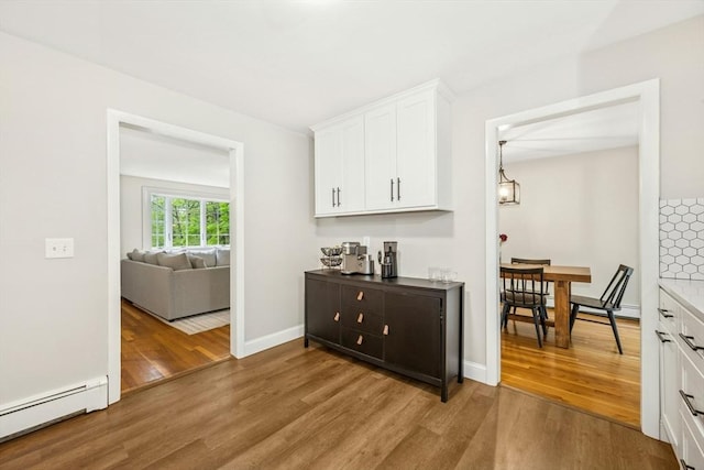 interior space featuring baseboards, wood finished floors, and a baseboard radiator