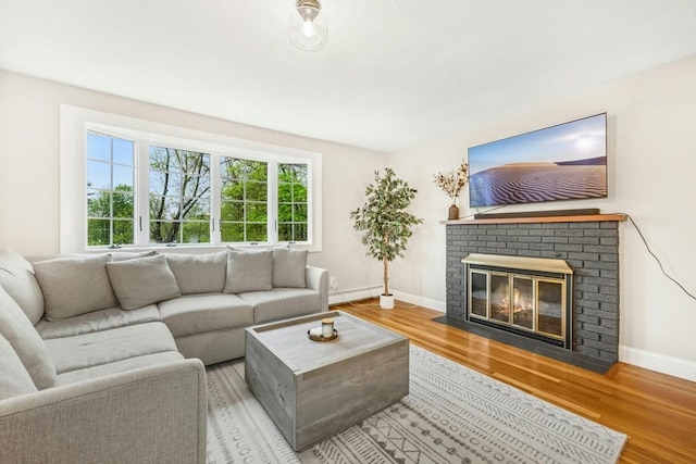 living room with baseboards, a baseboard radiator, a fireplace, and wood finished floors