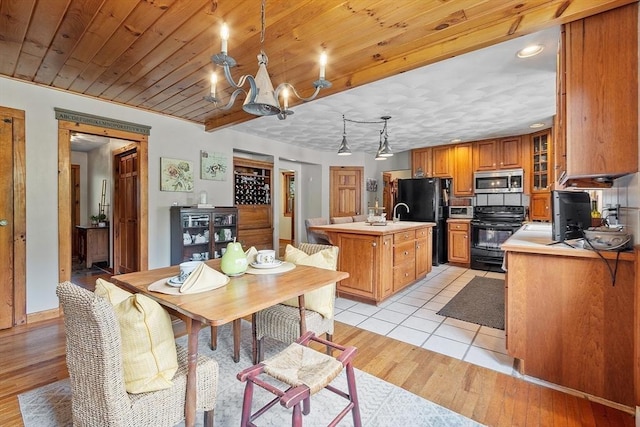 5 Vasa St, Billerica, MA 01862 - kitchen featuring black appliances, brown cabinetry, light countertops, a kitchen island with sink, and a chandelier
