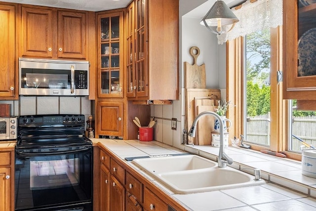 5 Vasa St, Billerica, MA 01862 - kitchen featuring electric range, stainless steel microwave, tile counters, brown cabinets, and glass insert cabinets
