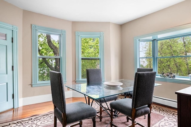 dining area featuring baseboard heating, wood finished floors, plenty of natural light, and baseboards