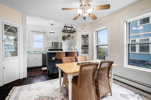 dining room with baseboard heating, hardwood / wood-style floors, and a ceiling fan