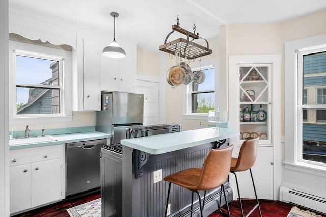 kitchen with appliances with stainless steel finishes, a baseboard heating unit, a sink, dark wood-style flooring, and light countertops