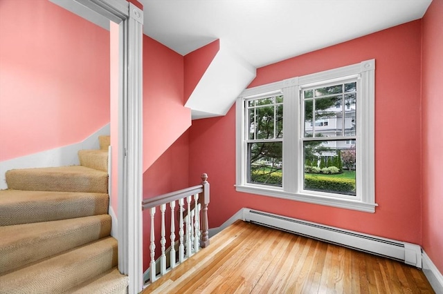 additional living space featuring baseboard heating and hardwood / wood-style flooring