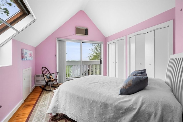 bedroom with light wood-style flooring, lofted ceiling, multiple closets, and a wall unit AC