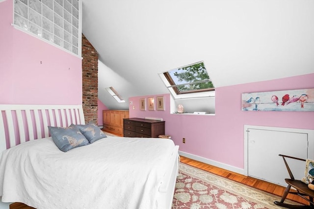 bedroom featuring a skylight, lofted ceiling, light wood-type flooring, and baseboards