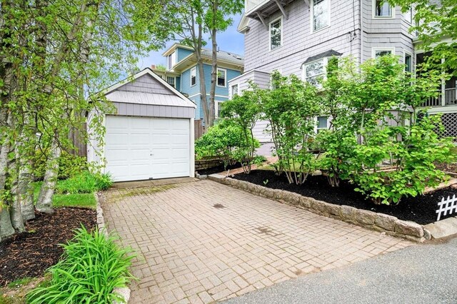 view of front of house with a garage, an outbuilding, and decorative driveway