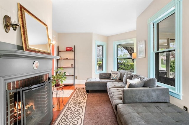 living area with a brick fireplace and wood finished floors
