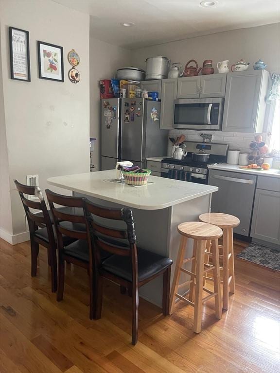 108 Grove St, Lynn, MA 01905 - kitchen featuring appliances with stainless steel finishes, light wood finished floors, a breakfast bar, gray cabinets, and recessed lighting