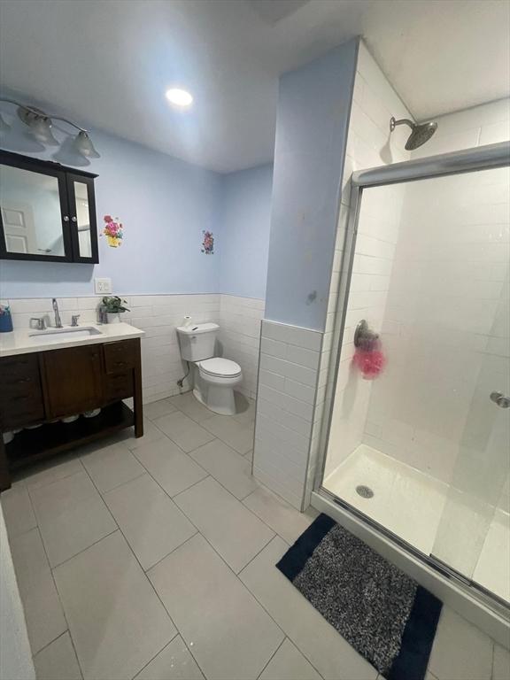 108 Grove St, Lynn, MA 01905 - bathroom with a shower stall, tile walls, vanity, wainscoting, and tile patterned flooring