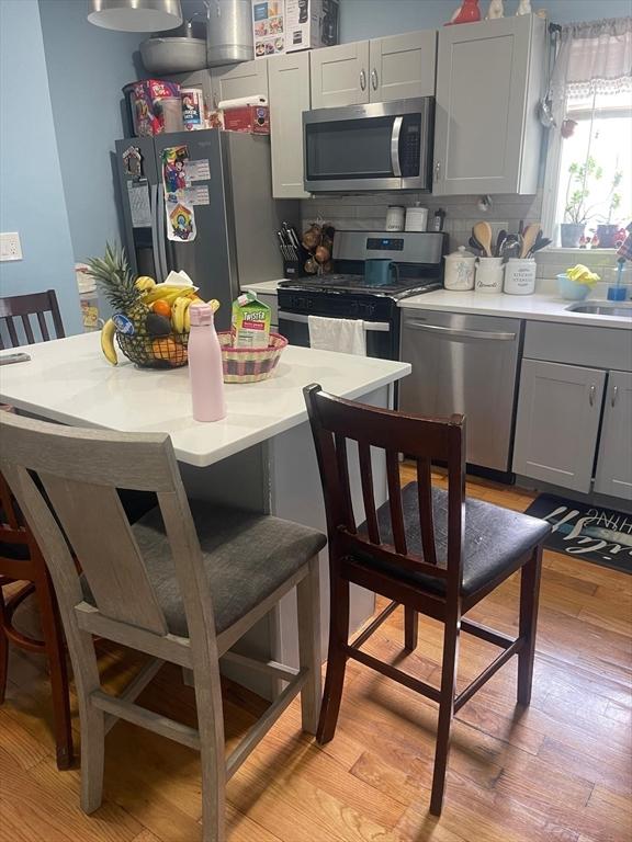 108 Grove St, Lynn, MA 01905 - kitchen with appliances with stainless steel finishes, gray cabinetry, light countertops, and light wood-style floors