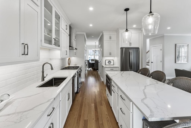 kitchen with decorative light fixtures, sink, white cabinets, a kitchen breakfast bar, and stainless steel appliances