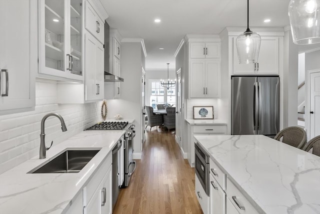 kitchen with appliances with stainless steel finishes, sink, white cabinets, and decorative light fixtures