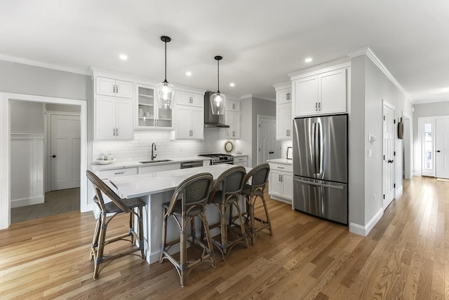 kitchen featuring a kitchen island, appliances with stainless steel finishes, decorative light fixtures, sink, and white cabinets