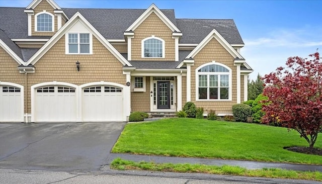 view of front facade with a shingled roof, a front yard, and aphalt driveway