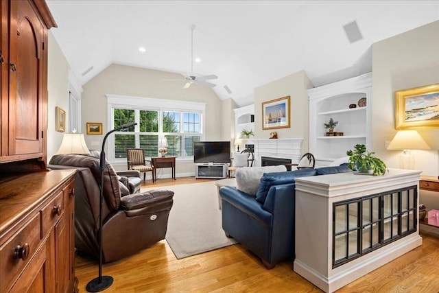 living area featuring lofted ceiling, light wood-style floors, a fireplace, and ceiling fan