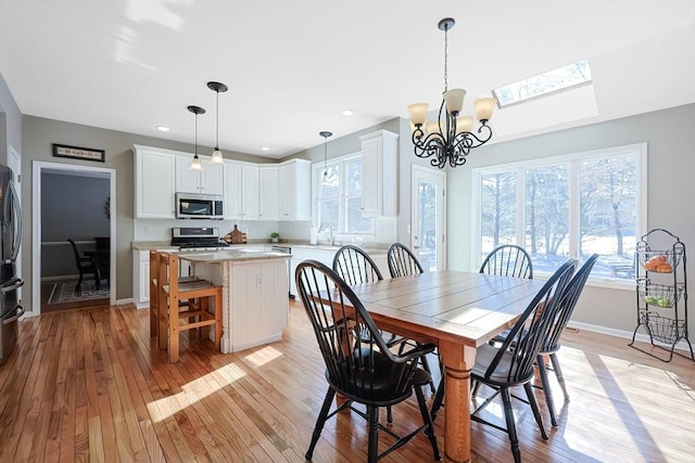 dining area with light wood finished floors, baseboards, a notable chandelier, and recessed lighting