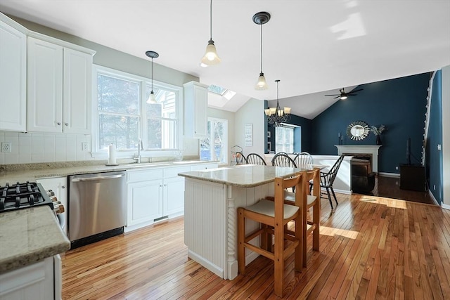 kitchen with light stone counters, stainless steel dishwasher, decorative light fixtures, and white cabinets