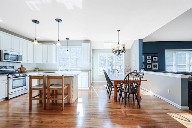 kitchen featuring stainless steel appliances, light countertops, a kitchen island, and white cabinetry