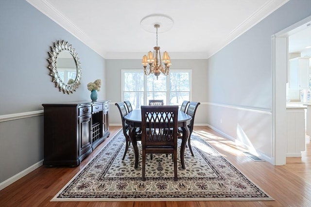 dining room with crown molding, dark wood-type flooring, baseboards, and a notable chandelier