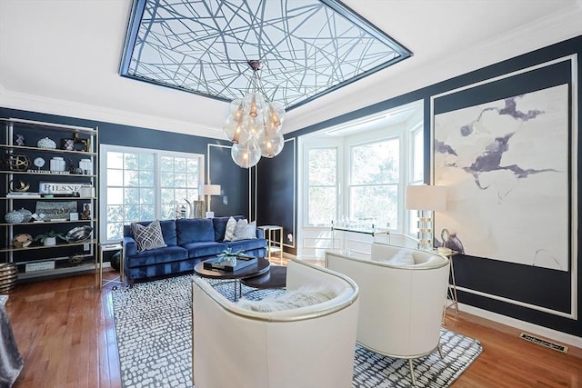 living room featuring a wealth of natural light, visible vents, crown molding, and wood finished floors