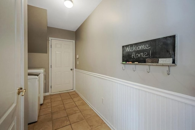 laundry area featuring washing machine and dryer, laundry area, a wainscoted wall, and light tile patterned floors