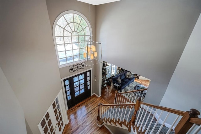 foyer featuring a wealth of natural light, a high ceiling, a notable chandelier, and wood finished floors