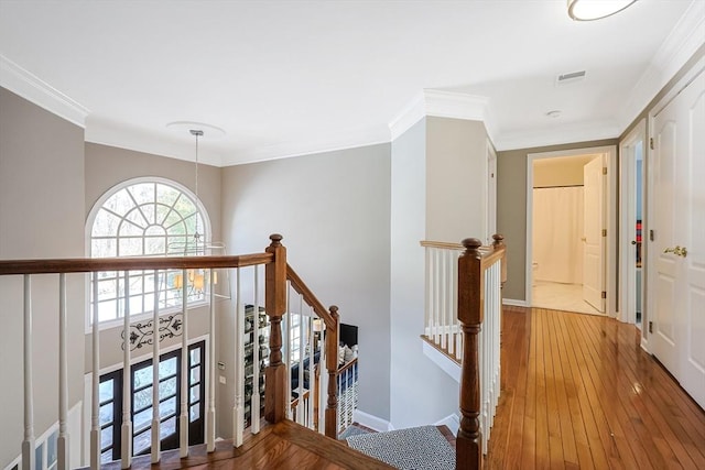 hall featuring ornamental molding, baseboards, an upstairs landing, and wood finished floors