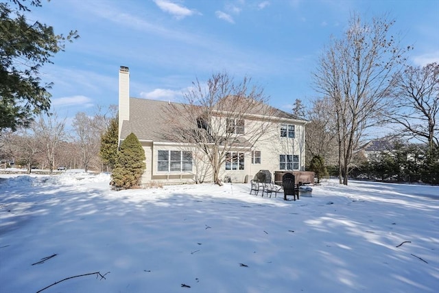 snow covered property featuring a jacuzzi and a chimney