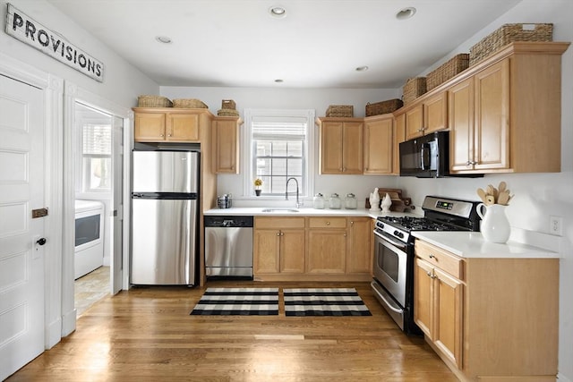 kitchen featuring stainless steel appliances, sink, hardwood / wood-style floors, and light brown cabinetry