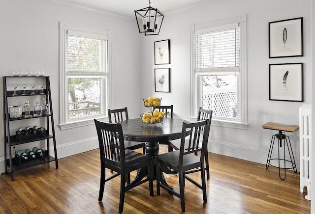 dining area with ornamental molding, hardwood / wood-style floors, and a notable chandelier