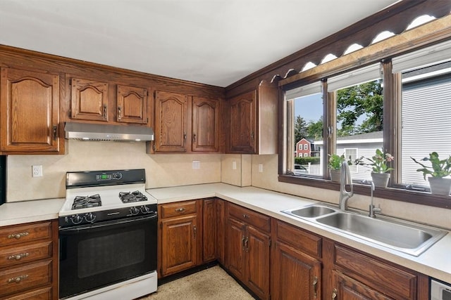 349 Pleasant St, Milton, MA 02186 - kitchen featuring black range with gas cooktop, under cabinet range hood, light countertops, and brown cabinets