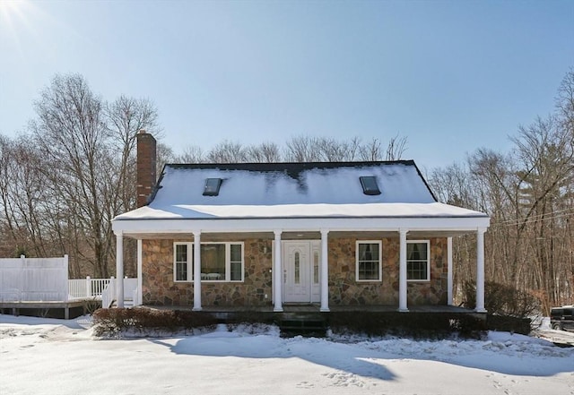 view of front of home featuring stone siding, a porch, and a chimney