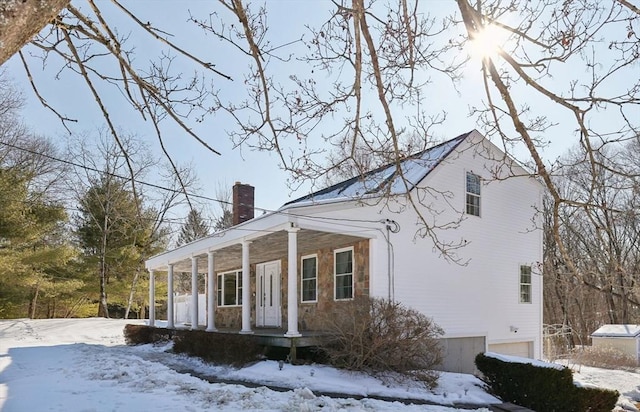 view of front of property featuring a garage, a porch, and a chimney