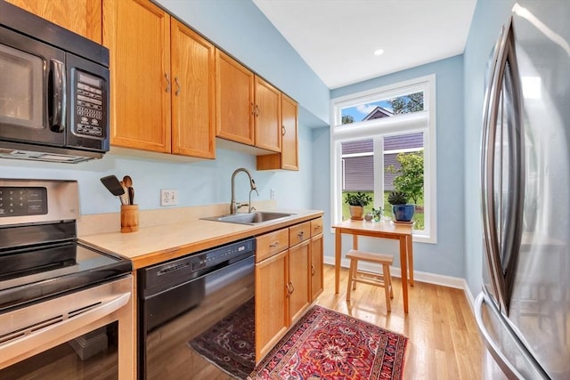 14 Michaels Grn Unit 14, Woburn, MA 01801 - kitchen featuring black appliances, a sink, light wood-style flooring, light countertops, and baseboards