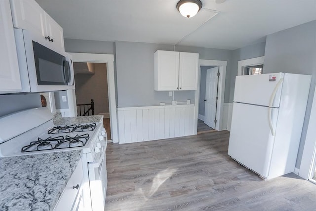 kitchen with white appliances, light stone counters, white cabinets, and light wood finished floors